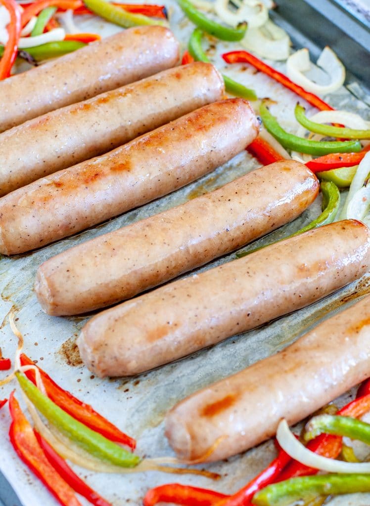 Cooked bratwurst peppers and onions on bakind sheet