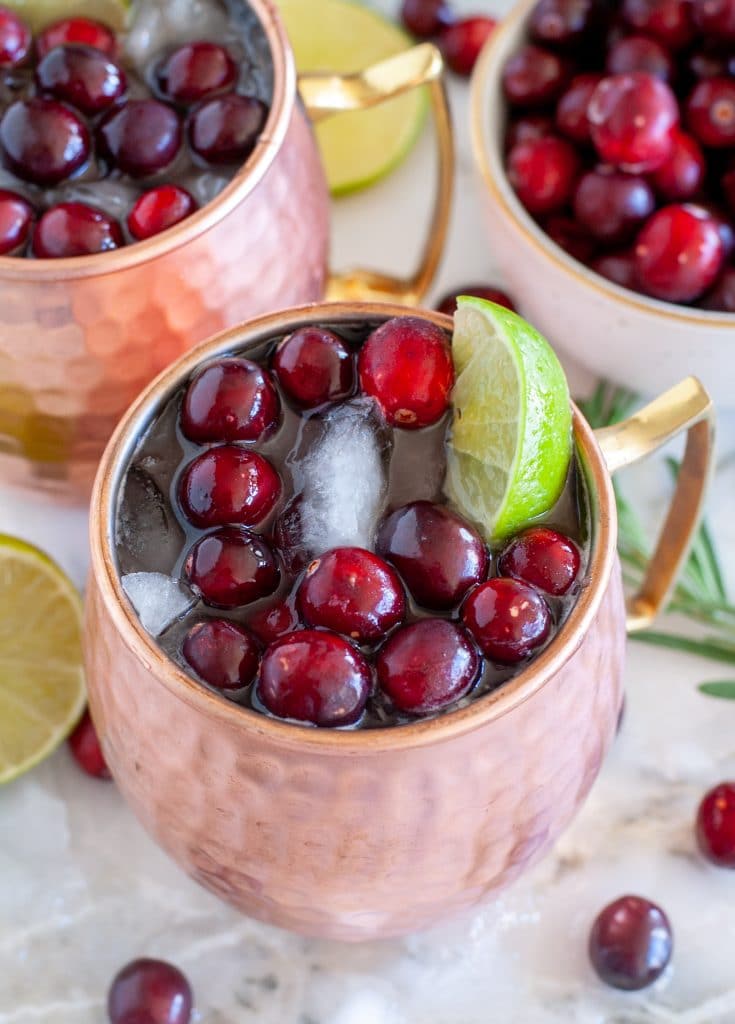 copper mug with cranberries, lime wedge and cranberry juice