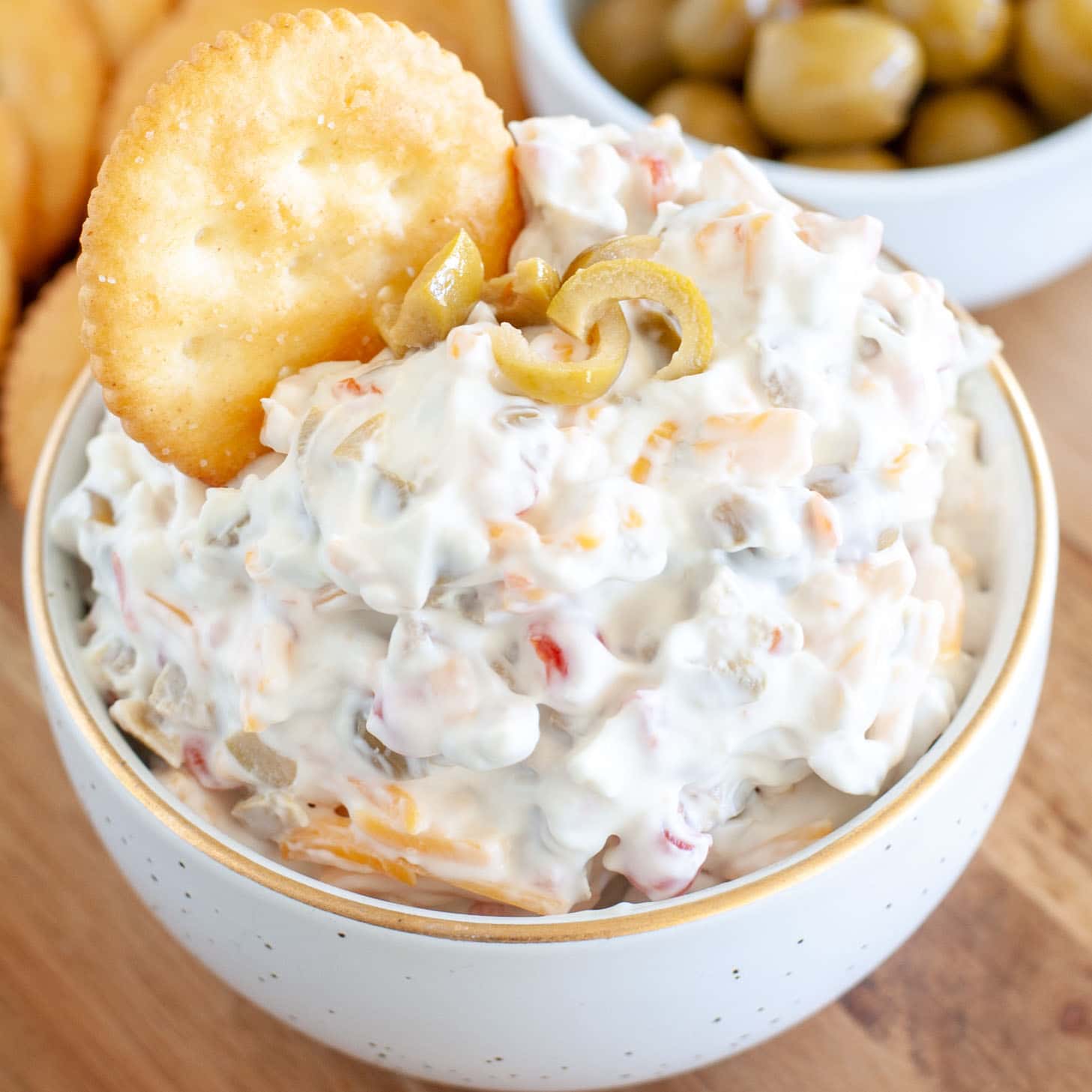 Bowl with dip made of cream cheese and olives. Bowl of olives and crackers.