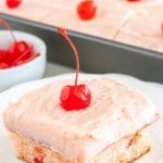 Piece of cake with pink frosting and cherry.