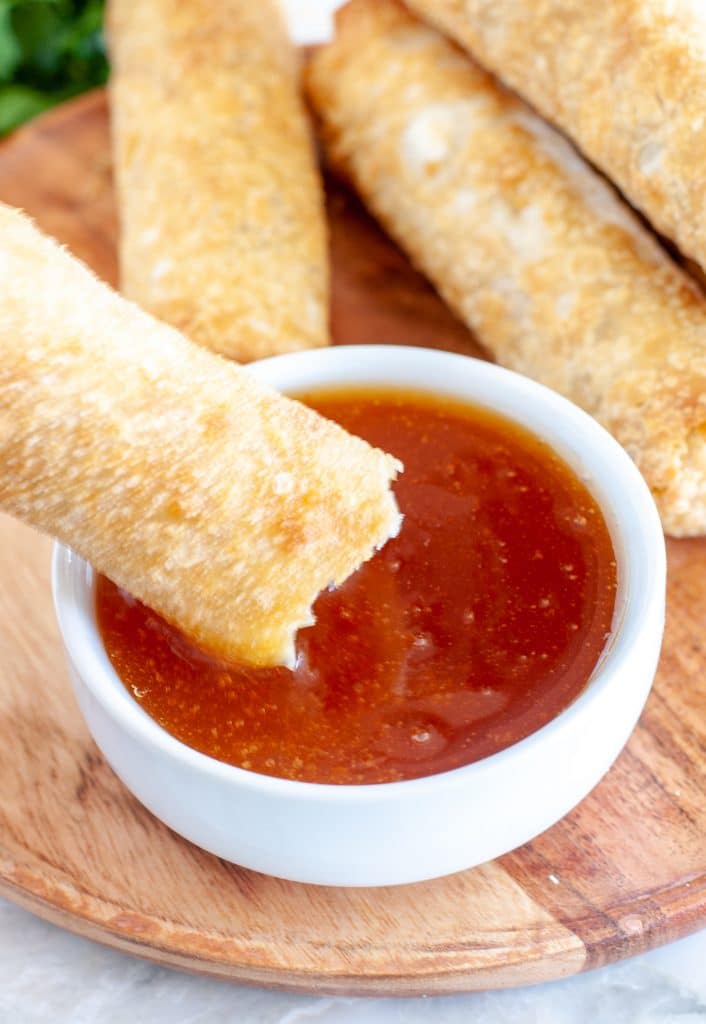 Egg Roll being dipped in sauce.