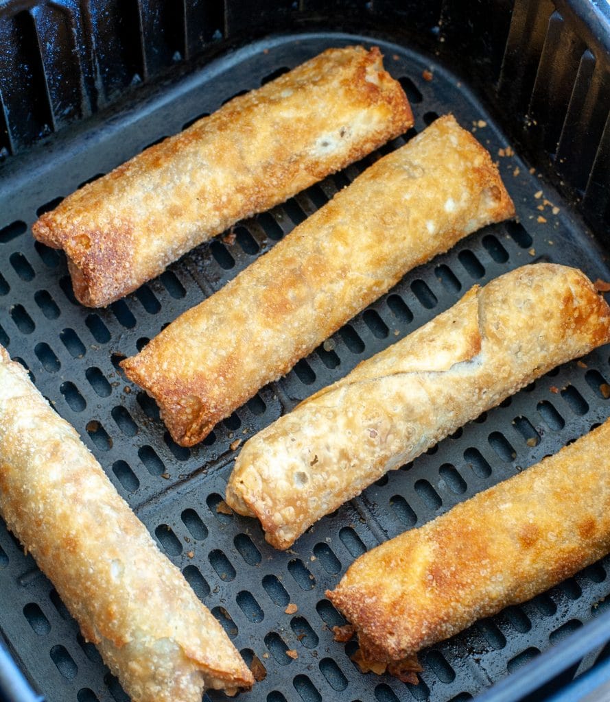 Egg rolls in an air fryer basket. 