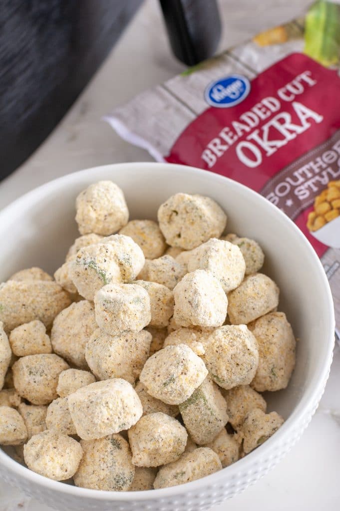 Frozen okra in a bowl with bag in the background. 