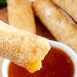 Egg roll dipping into sauce.