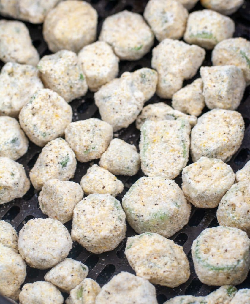 Uncooked breaded okra in air fryer basket. 