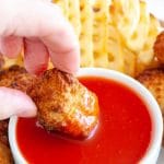 Sweet and sour sauce in bowl with chicken nugget.