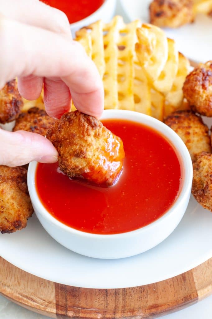 Bowl of sauce with chicken nugget. 