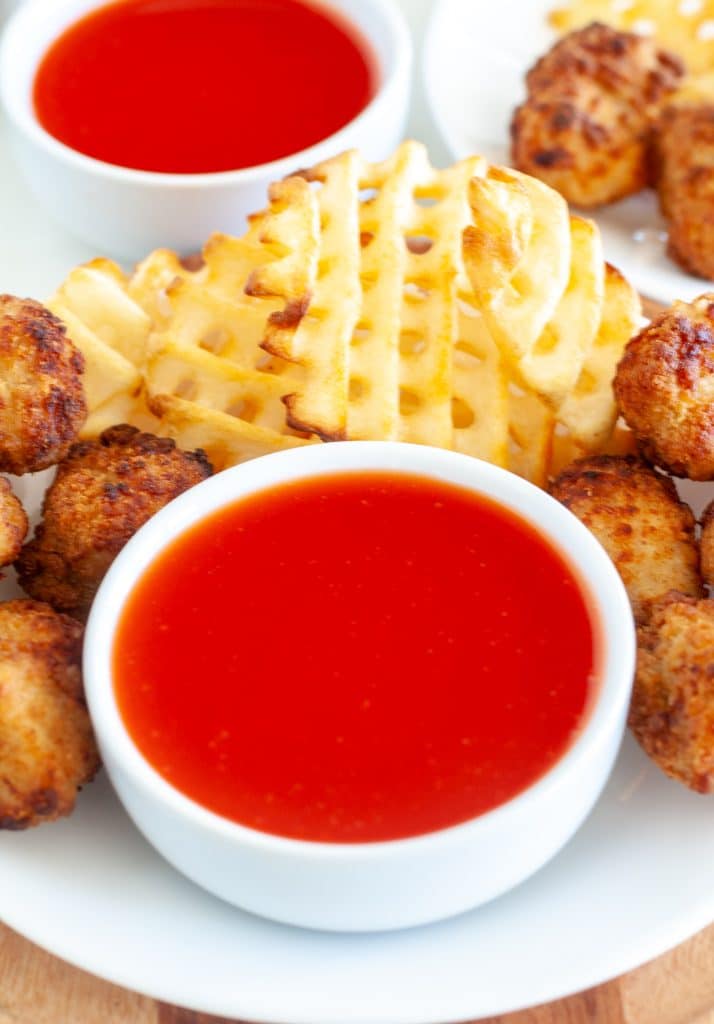 Bow of sweet and sour sauce surrounded by chicken nuggets. 