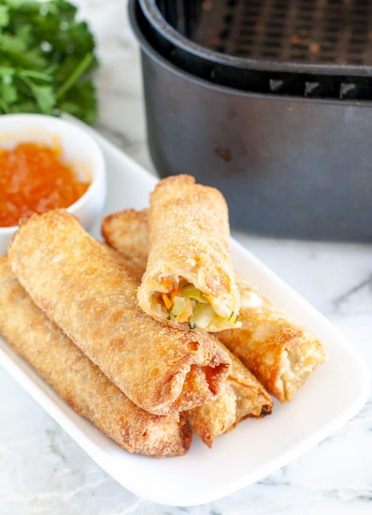 Egg rolls on a plate with sauce. 