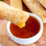 Bowl of sauce with egg roll dipping into it.