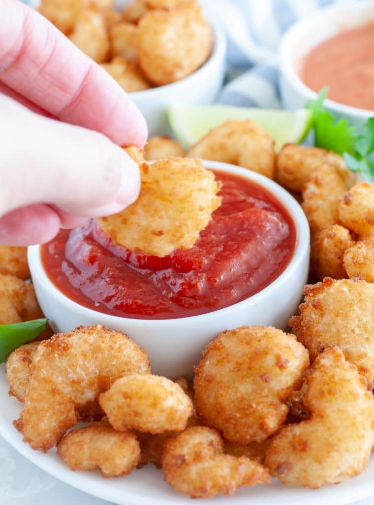 Hand dipping shrimp in sauce. 