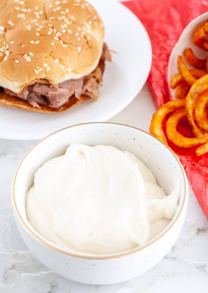 Bowl of cream sauce with a roast beef sandwich and fries. 