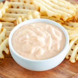 Bowl with mayonnaise sauce and waffle fries.