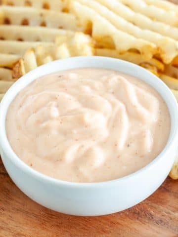 Bowl with mayonnaise sauce and waffle fries.