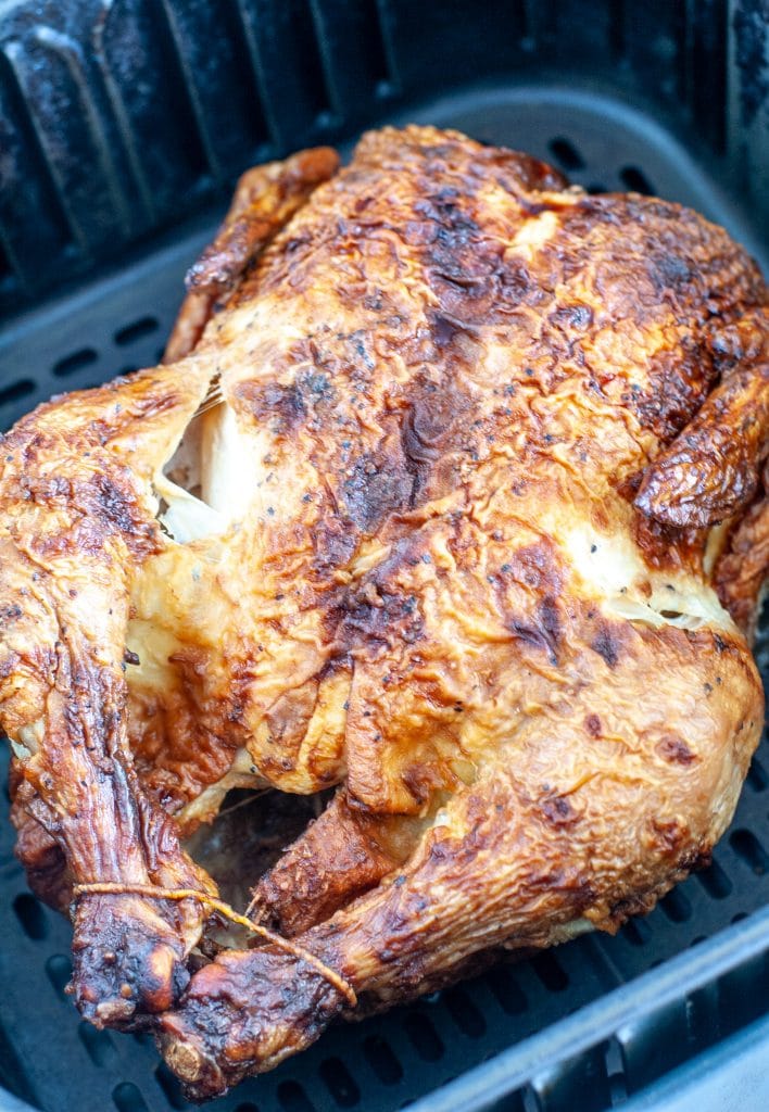 Whole chicken in air fryer basket.