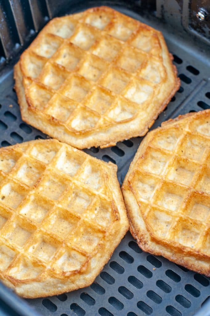 Cooked waffles in air fryer basket.