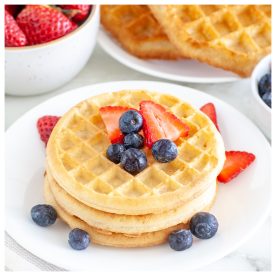 Stack of waffles on a plate with berries.