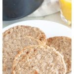 Sausage patties on a plate with glass of orange juice.