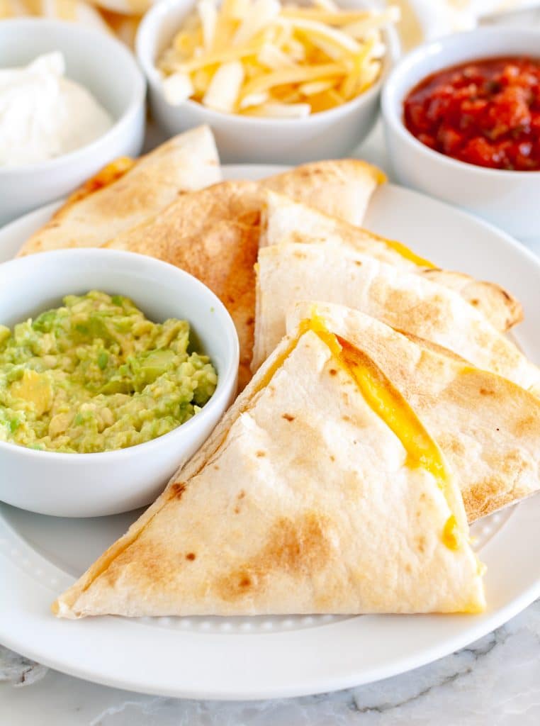 Quesadillas on a plate with bowl of guacamole. 
