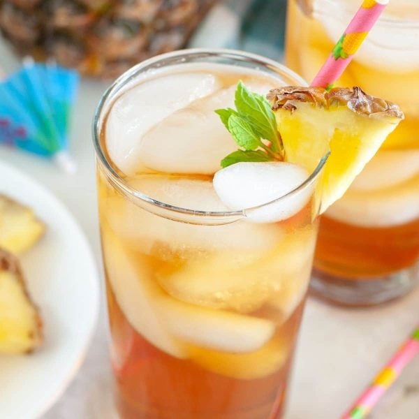 Glass of tea with piece of pineapple.