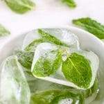 Mint leaves frozen in ice cubes in a bowl.