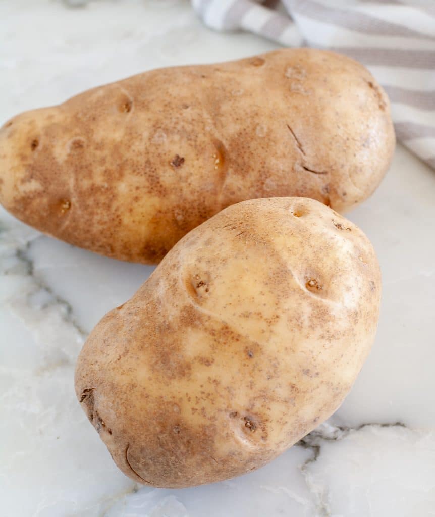 Two russet potatoes on table.