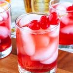 Glasses filled with red drink and cherries.