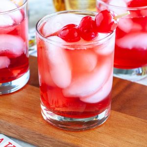 Glasses with red drink and cherries.