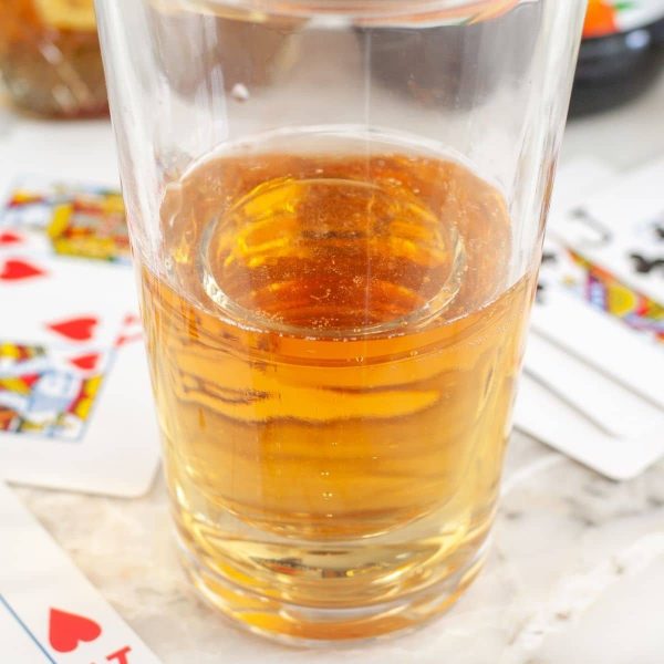 Glass filled with energy drink and playing cards beside the glass.