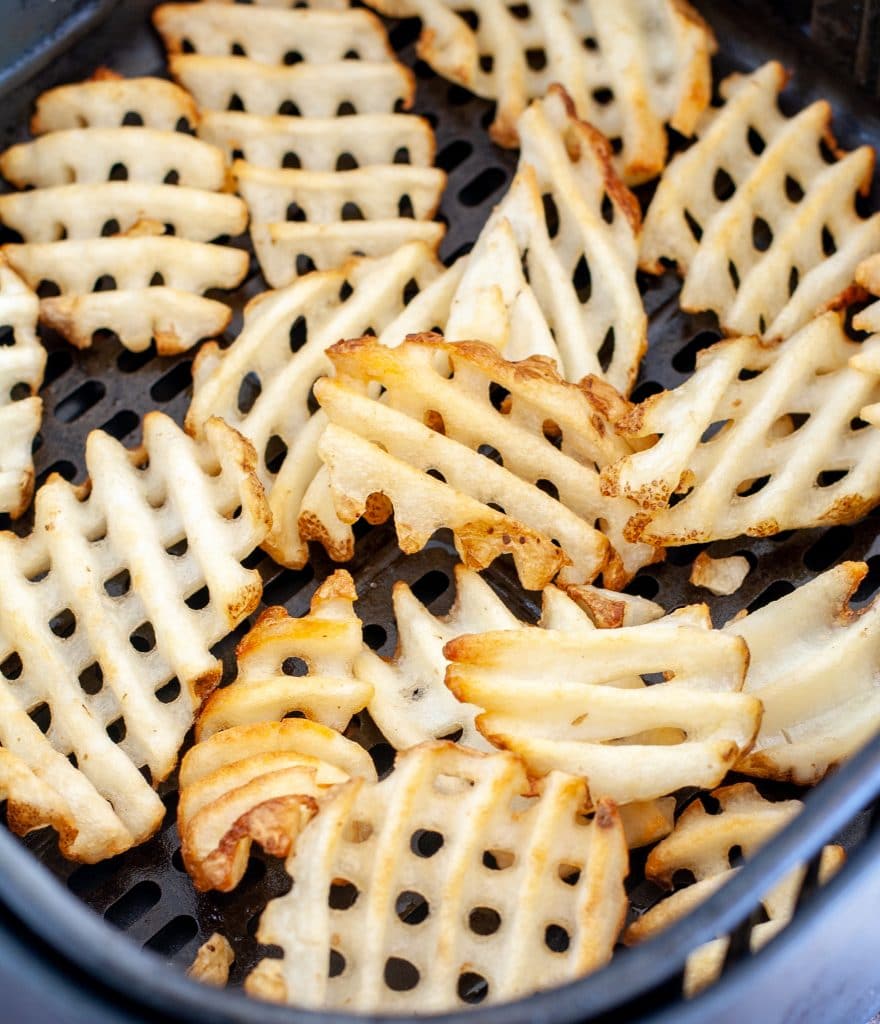 Cooked waffle fries in air fryer basket. 