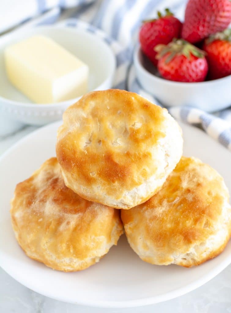 Plate of biscuits with bowl of butter and strawberries. 