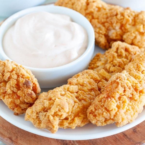 Plate of chicken tenders with bowl of sauce.