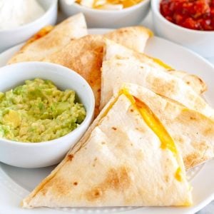 Quesadilla triangles on a plate with bowl of guacamole.
