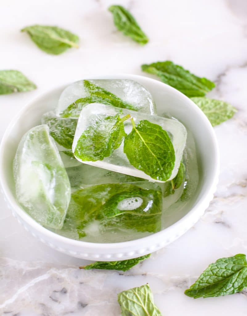 Mint leaves in ice cubes in a bowl.