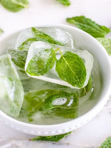 Mint leaves in ice cubes in a bowl.