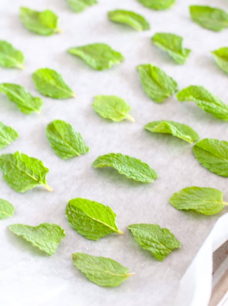 Mint leaves on parchment on a baking sheet.