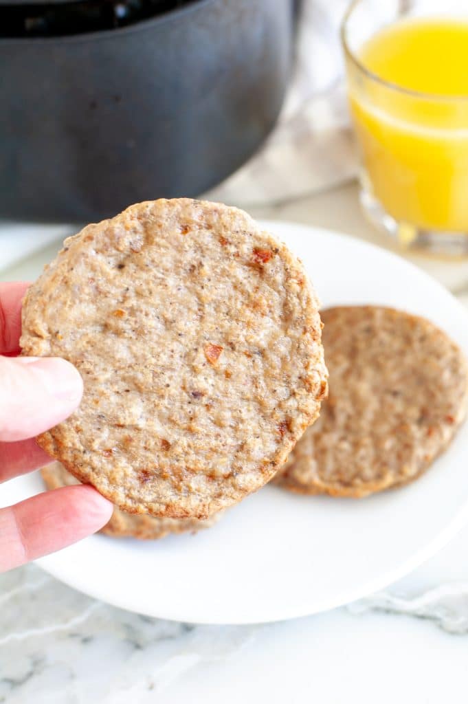 Hand holding cooked breakfast sausage patty. 