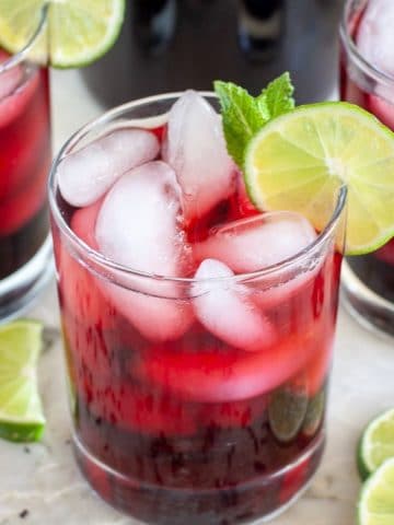 Glasses of hibiscus iced tea with lime slices.