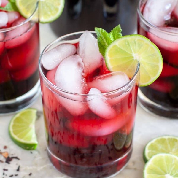 Glasses of hibiscus iced tea with lime slices.