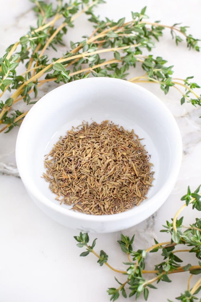 Bowl of dried thyme and fresh thyme.
