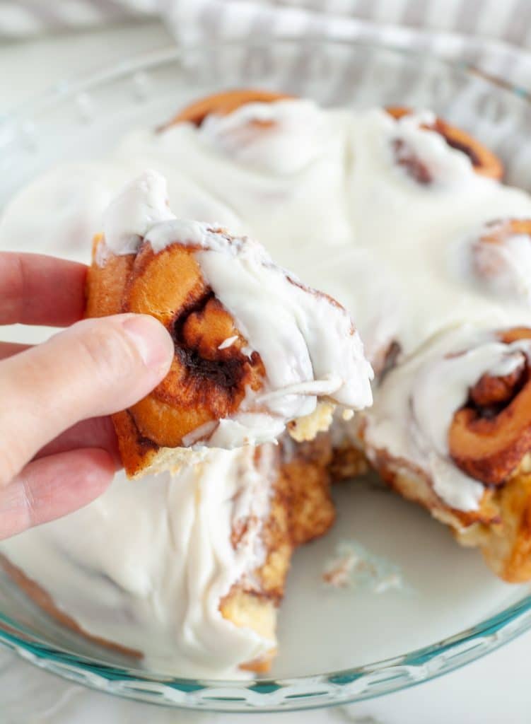 Hand holding a cinnamon roll. 