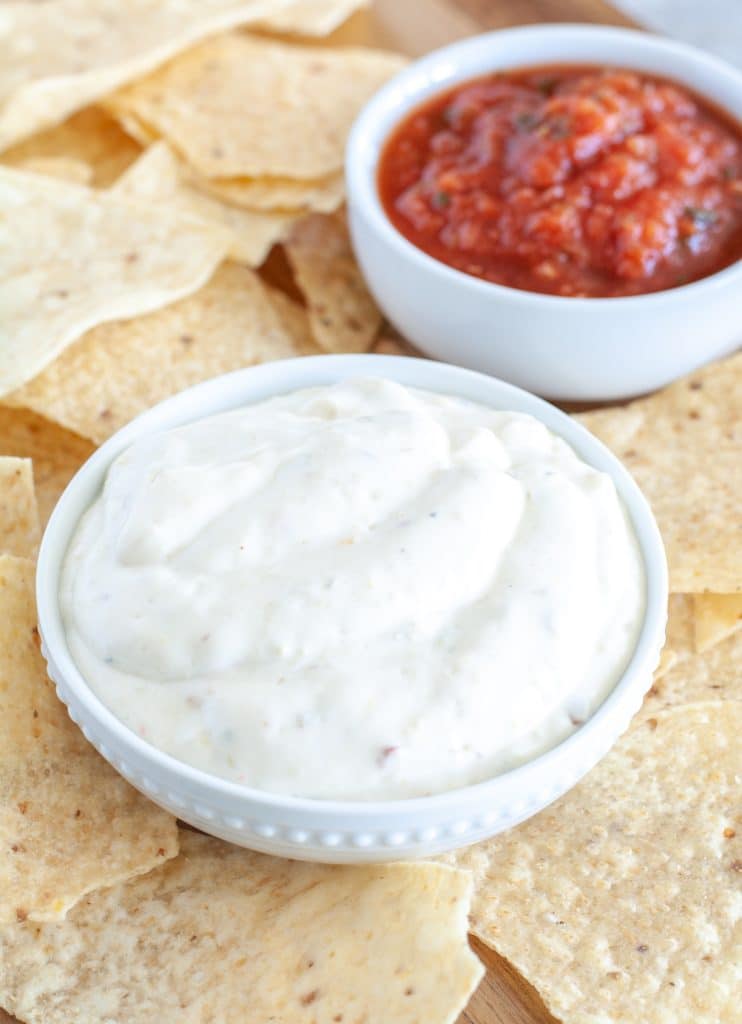 Bowl of white sauce, salsa and chips. 