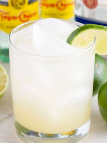 Clear drink in a glass with lime wedge.