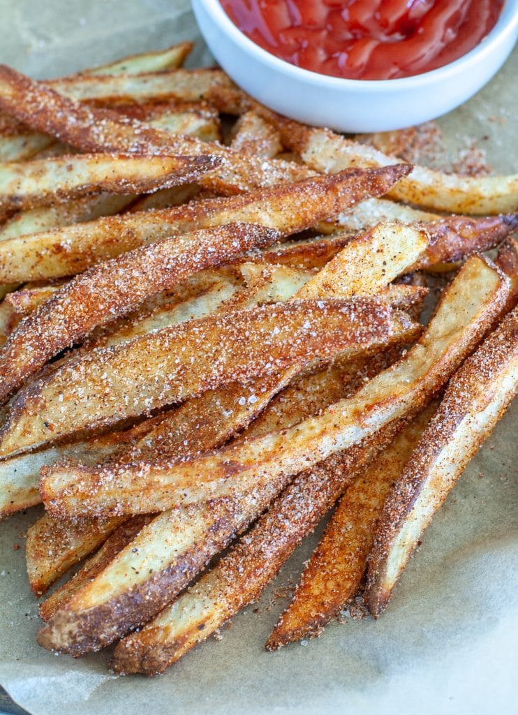 French fries on a plate with bowl of ketchup. 