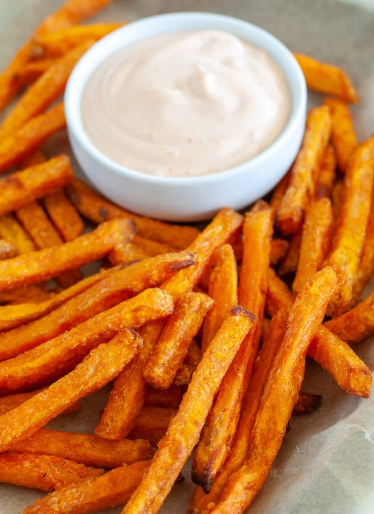 Sweet potato fries on plate with bowl of sauce. 