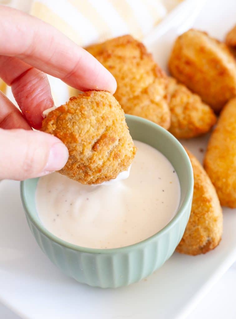 Hand dipping jalapeno popper in ranch. 