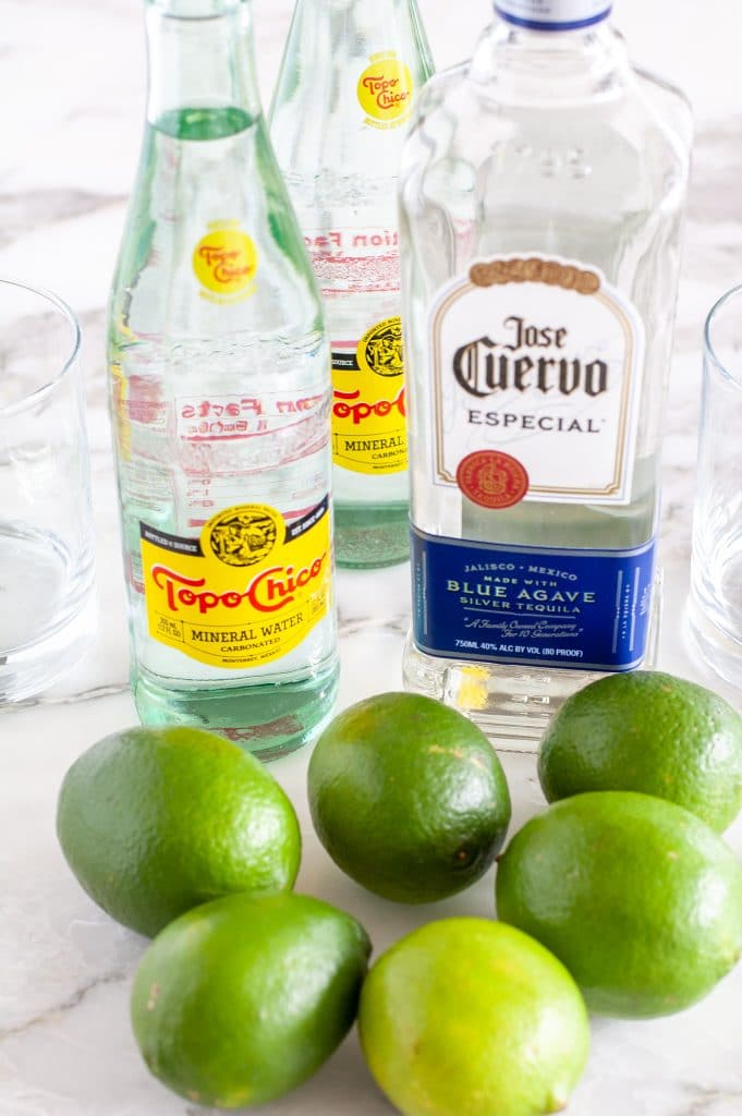 Bottle of Topo Chico, tequila and limes. 