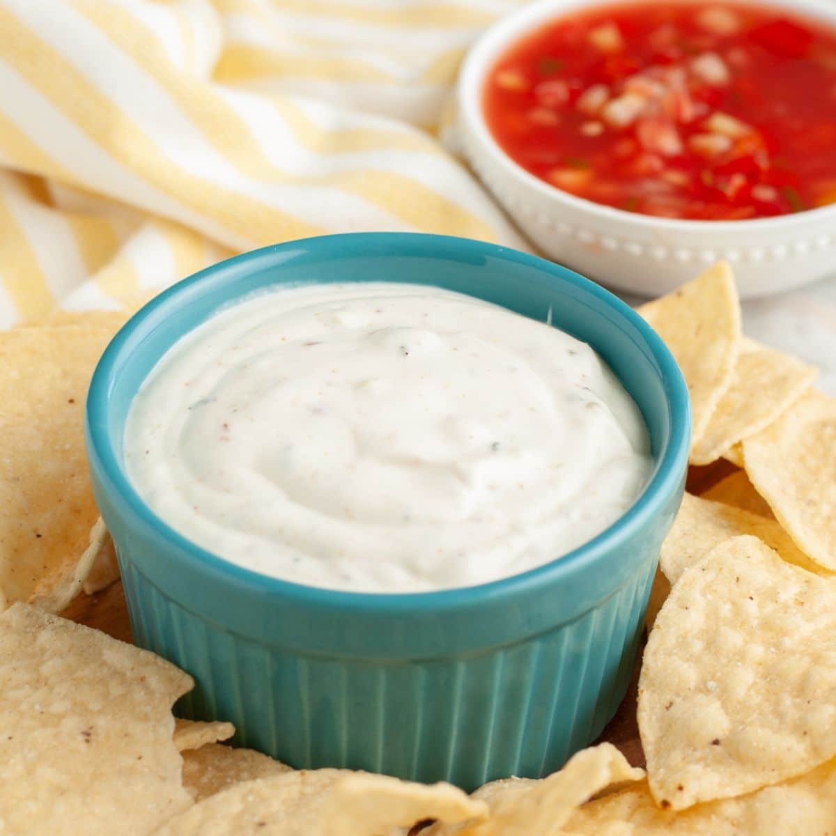 Bowl of white sauce, salsa, and tortilla chips.