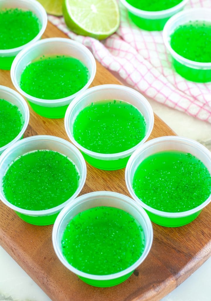 Small plastic cups with green JELLO. 