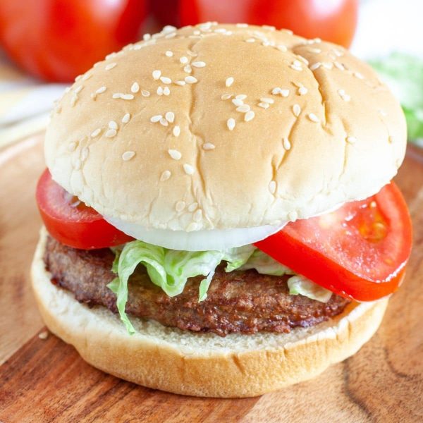 Burger on a plate with tomato and onion.
